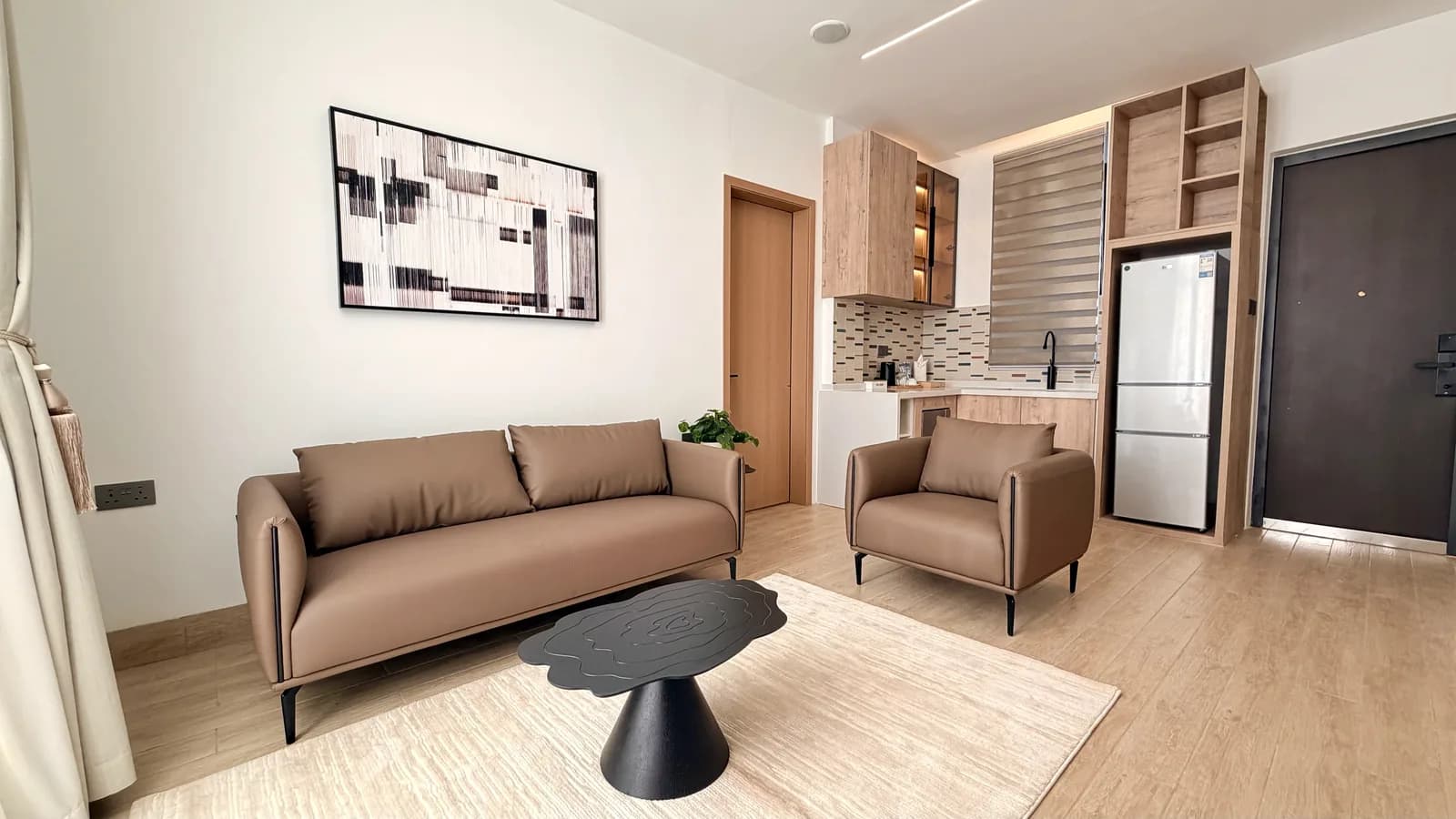 Tan leather lounge seating beside the kitchenette in a suite at HMK Living, Kigo Kampala